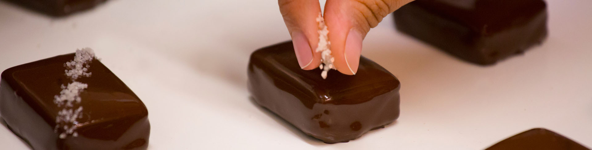 A photo of salt being meticulously applied to a piece of John Kelly Chocolate.