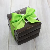 Three dark brown boxes stacked, They are tied together with a green ribbon.