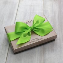 A closed eight piece assortment box. It is tied close with a bright green ribbon.