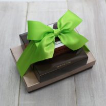 Three boxes of various sizes stacked on top of each other. The boxes are tied together with a green ribbon.
