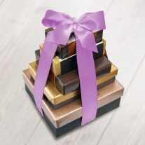 Five boxes of various size stacked from largest to smallest. They are tied together with an orchid color ribbon.
