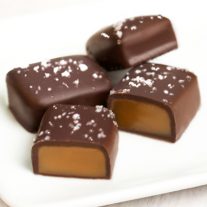 Four fleur de sel salted caramels. Two are cut open to reveal the gooey caramel inside.