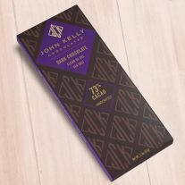 A dark brown, rectangular box. There is a purple diamond on it that holds a John Kelly Chocolates logo and the product name.