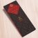A dark brown, rectangular box. There is a red diamond on it that holds a John Kelly Chocolates logo and the product name.