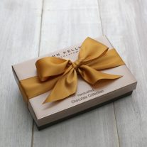 A closed eight piece assortment. The box is tied with a gold ribbon.