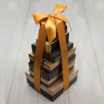 Eight boxes of various sizes stacked. They are tied together with a gold ribbon.