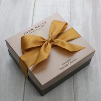 A closed 24 piece assortment. The box is square and has a gold ribbon on it.
