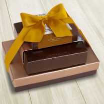 Four boxes of various sizes are stacked vertically from largest to smallest. They are tied together with a gold bow.