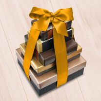 Fives boxes of various sizes stacked vertically from largest to smallest. They are tied together with a gold ribbon.