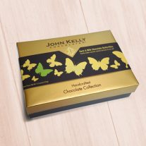 A closed nine piece butterfly box. The box has a gold lid with a brown sleeve. The sleeve has beautiful gold butterflies on it.