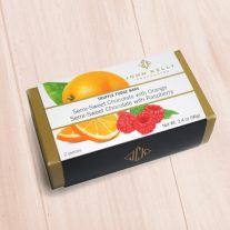 A gold box with a white sleeve. The sleeve has a drawing of an orange and some raspberries. A white box with a label on it.