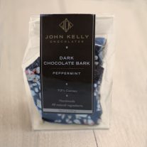 Dark chocolate peppermint bark is a clear, plastic, bag. The bag has a dark brown label on it with a gold John Kelly Chocolate logo.