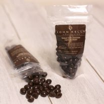 Two bags of chocolate covered espresso beans. One is standing up. The other is laying down, mostly empty with the beans sitting in front of the open bag.