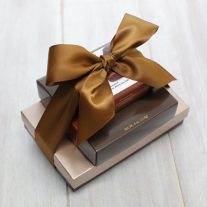 Three boxes of various sizes stacked on top of each other. They are tied together with a brown ribbon.