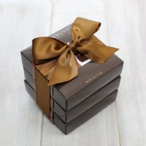 Three dark brown boxes stacked. A brown ribbon ties them together.