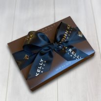 A closed 8 piece dark assortment with a black John Kelly Chocolates ribbon