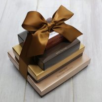 Four boxes of various sizes stacked. They are tied together with a brown ribbon.