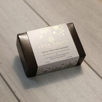 A dark brown box with a white sleeve. The white sleeve has gold snowflakes on it and a John Kelly Chocolates logo in a center. Underneath the logo is the product name.