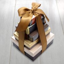 Five boxes of assorted sizes stacked largest to smallest at the top. They are tied together with a brown ribbon.