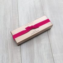 A closed 4 piece assortment box with a fuchsia ribbon