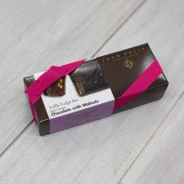 A chocolate with walnuts 8oz bar box with a fuchsia ribbon. The box is brown and has a label on it with an image of the CW on the semi-sweet chocolate with walnuts bar.