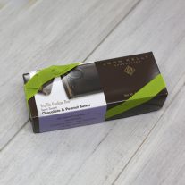 A dark brown rectangular box with a purple semi-sweet peanut butter chocolate sleeve on it. It is closed with a lime stretchy ribbon.