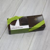 A dark brown rectangular box with a green semi-sweet chocolate sleeve on it. It is closed with a lime stretchy ribbon.