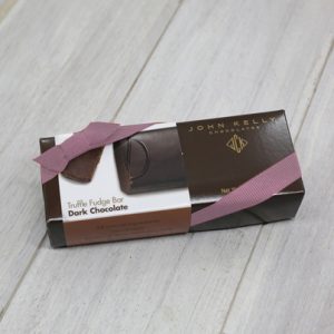 A dark brown rectangular box with a light brown dark chocolate sleeve on it. It is closed with an orchid stretchy ribbon.