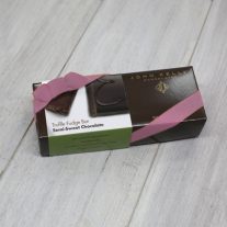 A dark brown rectangular box with a green semi-sweet chocolate sleeve on it. It is closed with an orchid stretchy ribbon.
